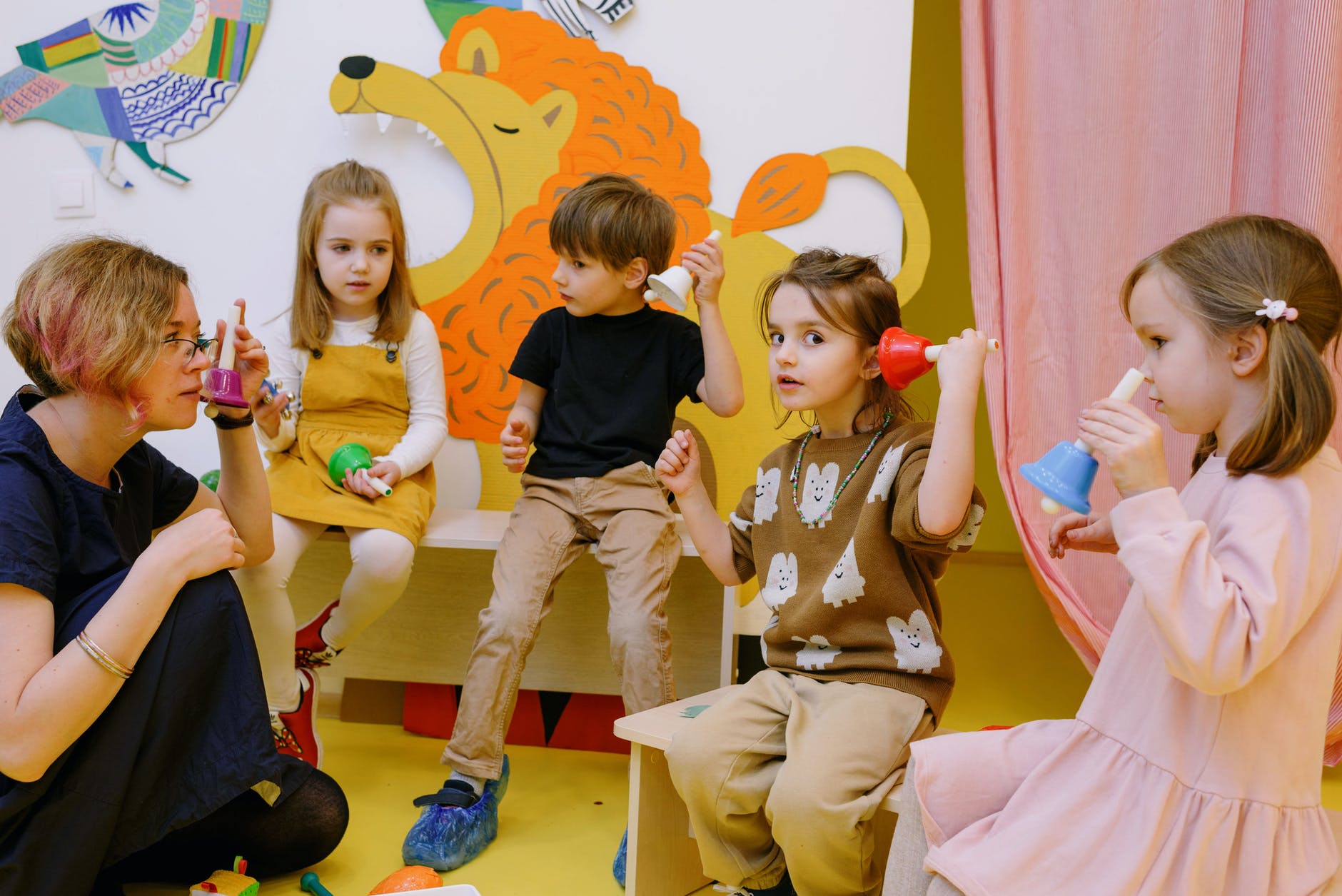 children with her students holding different color bells